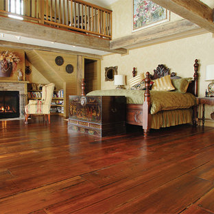 Imagen de dormitorio principal, clásico, grande, con paredes blancas, suelo de madera en tonos medios, chimenea tradicional y marco de chimenea de ladrillo
