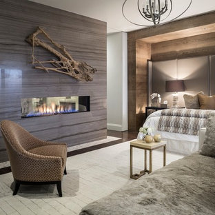 Ejemplo de dormitorio principal, actual, con suelo de madera oscura, chimenea de doble cara y marco de chimenea de baldosas y/o azulejos