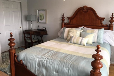 Imagen de dormitorio principal tradicional de tamaño medio sin chimenea con paredes grises, suelo de madera en tonos medios y suelo marrón