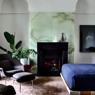 This is an example of a modern bedroom in Los Angeles with grey walls, carpet, a standard fireplace and brown floor.