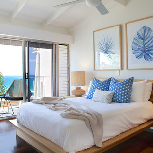 This is an example of a beach style master bedroom in Sunshine Coast with beige walls, dark hardwood floors and brown floor.