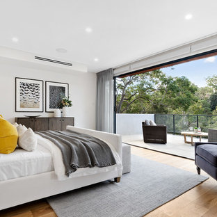 Contemporary bedroom in Sydney with white walls, medium hardwood floors and brown floor.