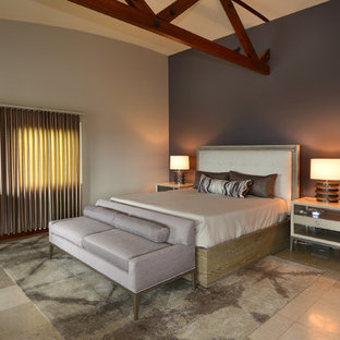 Modelo de dormitorio principal, contemporáneo, grande, con paredes beige, suelo de piedra caliza, chimenea tradicional, marco de chimenea de piedra y suelo gris