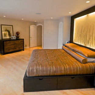 Foto de dormitorio principal, actual, grande, con paredes beige, suelo de madera clara, chimenea de esquina y marco de chimenea de metal
