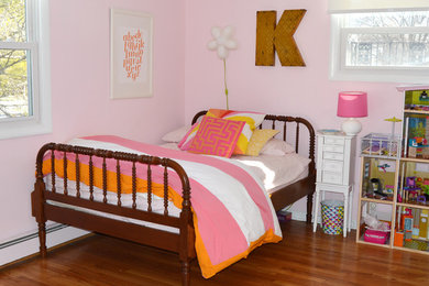 Foto de habitación de invitados retro de tamaño medio sin chimenea con suelo de madera en tonos medios y paredes rosas