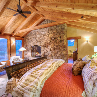 Diseño de dormitorio principal, de estilo americano, grande, con paredes amarillas, chimenea tradicional y marco de chimenea de piedra