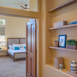 Modelo de dormitorio principal, de estilo americano, de tamaño medio, sin chimenea, con paredes amarillas, suelo de travertino y suelo marrón