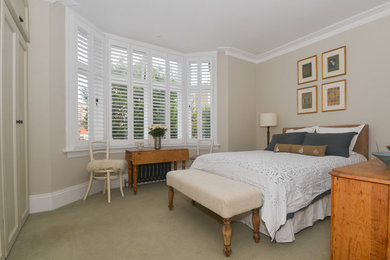 Medium sized classic master bedroom in Sussex with beige walls, carpet and beige floors.