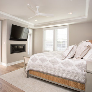 Immagine di una grande camera matrimoniale costiera con pareti beige, parquet chiaro, camino lineare Ribbon e pavimento beige