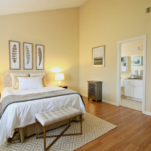 Modelo de dormitorio principal, contemporáneo, de tamaño medio, con paredes amarillas y suelo de madera en tonos medios