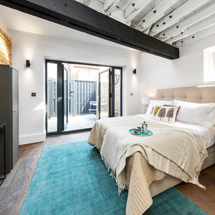 This is an example of an urban bedroom in Other with white walls, dark hardwood flooring, no fireplace and brown floors.
