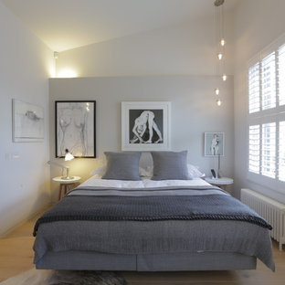 Modelo de dormitorio principal, contemporáneo, de tamaño medio, sin chimenea, con paredes blancas, suelo de madera clara y suelo beige