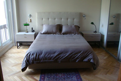 Immagine di una camera matrimoniale moderna con pareti beige e parquet chiaro