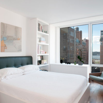 Example of a trendy loft-style medium tone wood floor bedroom design in New York with white walls