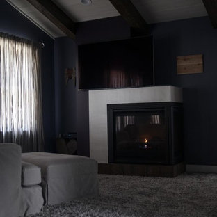 Foto de dormitorio principal, minimalista, grande, con paredes púrpuras, moqueta, chimenea de doble cara, marco de chimenea de madera y suelo gris