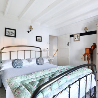 Diseño de dormitorio principal, de estilo de casa de campo, pequeño, con paredes blancas, suelo de madera pintada, chimenea tradicional y marco de chimenea de ladrillo
