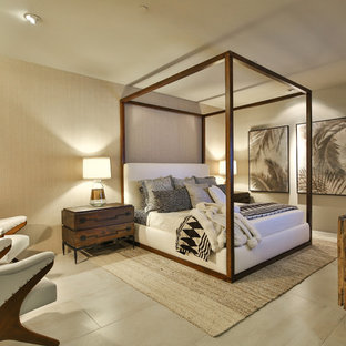 Ejemplo de habitación de invitados tropical, grande, sin chimenea, con paredes beige, suelo de baldosas de porcelana, marco de chimenea de piedra y suelo beige