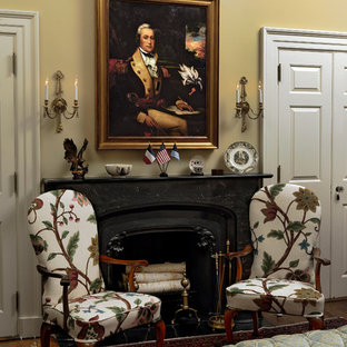 Foto de habitación de invitados clásica, de tamaño medio, con paredes amarillas, suelo de madera en tonos medios, marco de chimenea de piedra, chimenea tradicional y suelo marrón