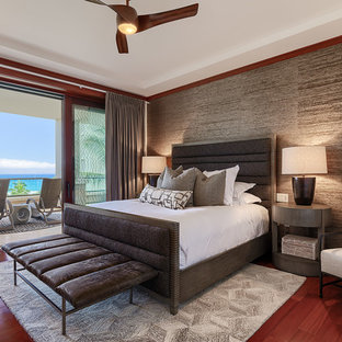 Cette photo montre une grand chambre parentale tendance avec un mur gris, un sol en bois brun, un sol rouge et aucune cheminée.