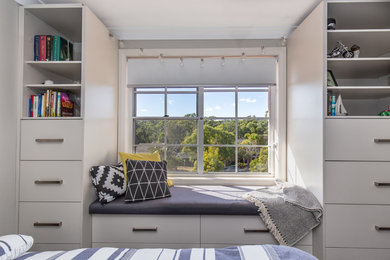 Modelo de habitación de invitados contemporánea grande sin chimenea con paredes grises, suelo de madera en tonos medios y suelo gris