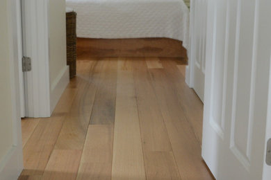 Elegant master medium tone wood floor and brown floor bedroom photo in Other with beige walls