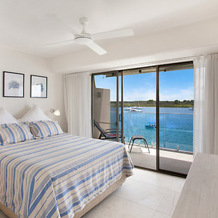 Imagen de dormitorio principal, marinero, grande, sin chimenea, con paredes amarillas y suelo de travertino