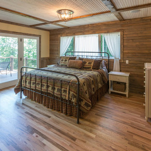 Imagen de dormitorio principal, rural, de tamaño medio, con paredes multicolor, suelo de madera clara, chimenea tradicional, marco de chimenea de piedra y suelo multicolor