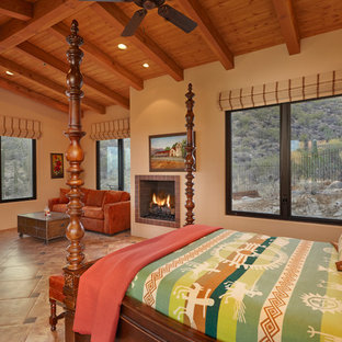 Modelo de habitación de invitados de estilo americano, grande, con paredes beige, chimenea tradicional, suelo de baldosas de porcelana y marco de chimenea de baldosas y/o azulejos