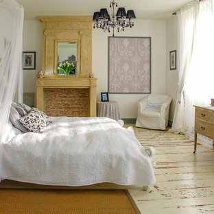 Cette image montre une chambre d'amis rustique de taille moyenne avec un mur blanc, un sol en bois peint, une cheminée standard, un manteau de cheminée en pierre et un sol blanc.