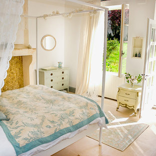 Ejemplo de habitación de invitados de estilo de casa de campo, de tamaño medio, con paredes blancas, suelo de travertino, chimenea tradicional, marco de chimenea de piedra y suelo beige