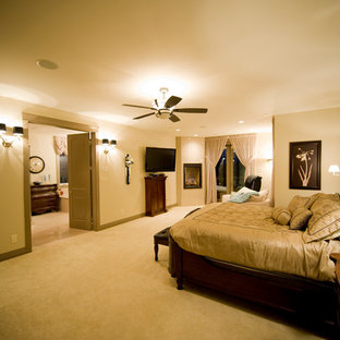 Imagen de dormitorio principal, grande, con paredes beige, moqueta, chimenea de esquina y marco de chimenea de yeso