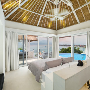 Diseño de dormitorio principal, tropical, grande, sin chimenea, con paredes blancas y suelo de piedra caliza