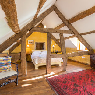 Modelo de dormitorio tipo loft, rústico, de tamaño medio, con paredes amarillas, suelo de madera oscura y suelo marrón