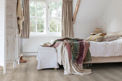 Ejemplo de dormitorio rural con suelo laminado y suelo beige
