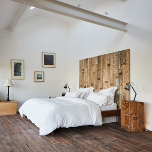 Imagen de dormitorio principal, rural, grande, sin chimenea, con paredes blancas, suelo de madera oscura y suelo marrón