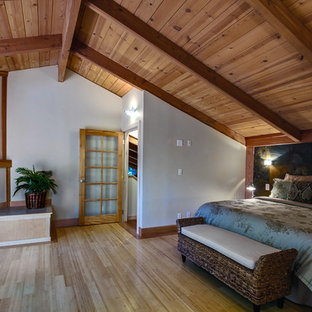 Diseño de dormitorio principal, de estilo americano, grande, con paredes beige, suelo de bambú, chimenea de esquina y marco de chimenea de madera