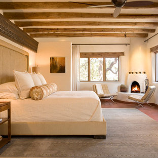 Inspiration for a large southwestern master bedroom remodel in Albuquerque with beige walls, a corner fireplace and a plaster fireplace