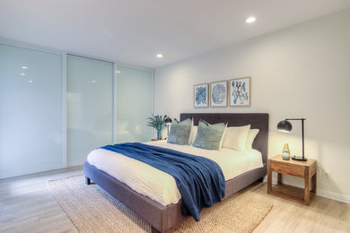 ロサンゼルスにある中くらいなビーチスタイルのおしゃれな主寝室 (白い壁、淡色無垢フローリング)