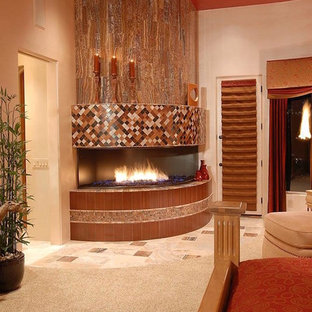 Modelo de dormitorio principal, mediterráneo, grande, con paredes beige, moqueta, chimenea de esquina, marco de chimenea de baldosas y/o azulejos y suelo gris