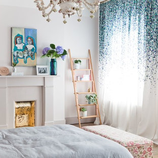 Inspiration for a romantic bedroom in London with white walls, light hardwood flooring, a standard fireplace and beige floors.