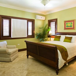 Imagen de habitación de invitados tropical, de tamaño medio, con paredes verdes y suelo de travertino