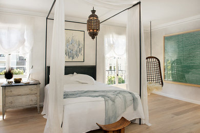 Réalisation d'une grande chambre parentale bohème avec un mur blanc et parquet clair.