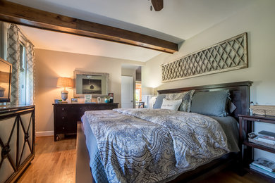 Imagen de dormitorio principal de estilo de casa de campo de tamaño medio sin chimenea con paredes beige y suelo de madera clara