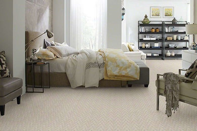 Cette photo montre une grande chambre tendance avec un mur blanc, aucune cheminée et un sol beige.