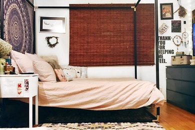 Imagen de dormitorio principal ecléctico de tamaño medio sin chimenea con paredes blancas, suelo de madera en tonos medios y suelo marrón