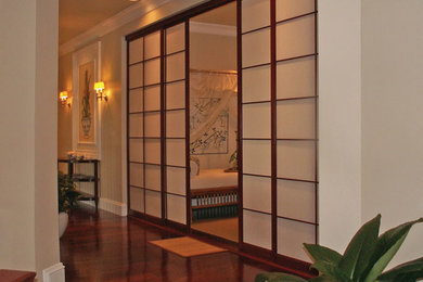 Imagen de habitación de invitados asiática de tamaño medio sin chimenea con paredes beige y suelo de madera oscura