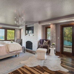 Mittelgroßes Klassisches Hauptschlafzimmer mit lila Wandfarbe, braunem Holzboden, Kamin, Kaminumrandung aus gestapelten Steinen, buntem Boden und eingelassener Decke in Milwaukee