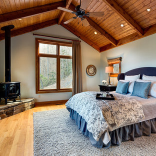 Foto de dormitorio principal, rural, grande, con paredes beige, suelo de madera clara, estufa de leña y suelo marrón