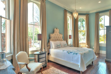 Foto di una camera da letto chic con pareti blu, pavimento in legno massello medio e nessun camino