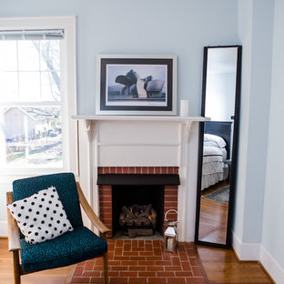 Imagen de habitación de invitados clásica renovada, de tamaño medio, con paredes azules, suelo de madera en tonos medios, chimenea tradicional y marco de chimenea de ladrillo